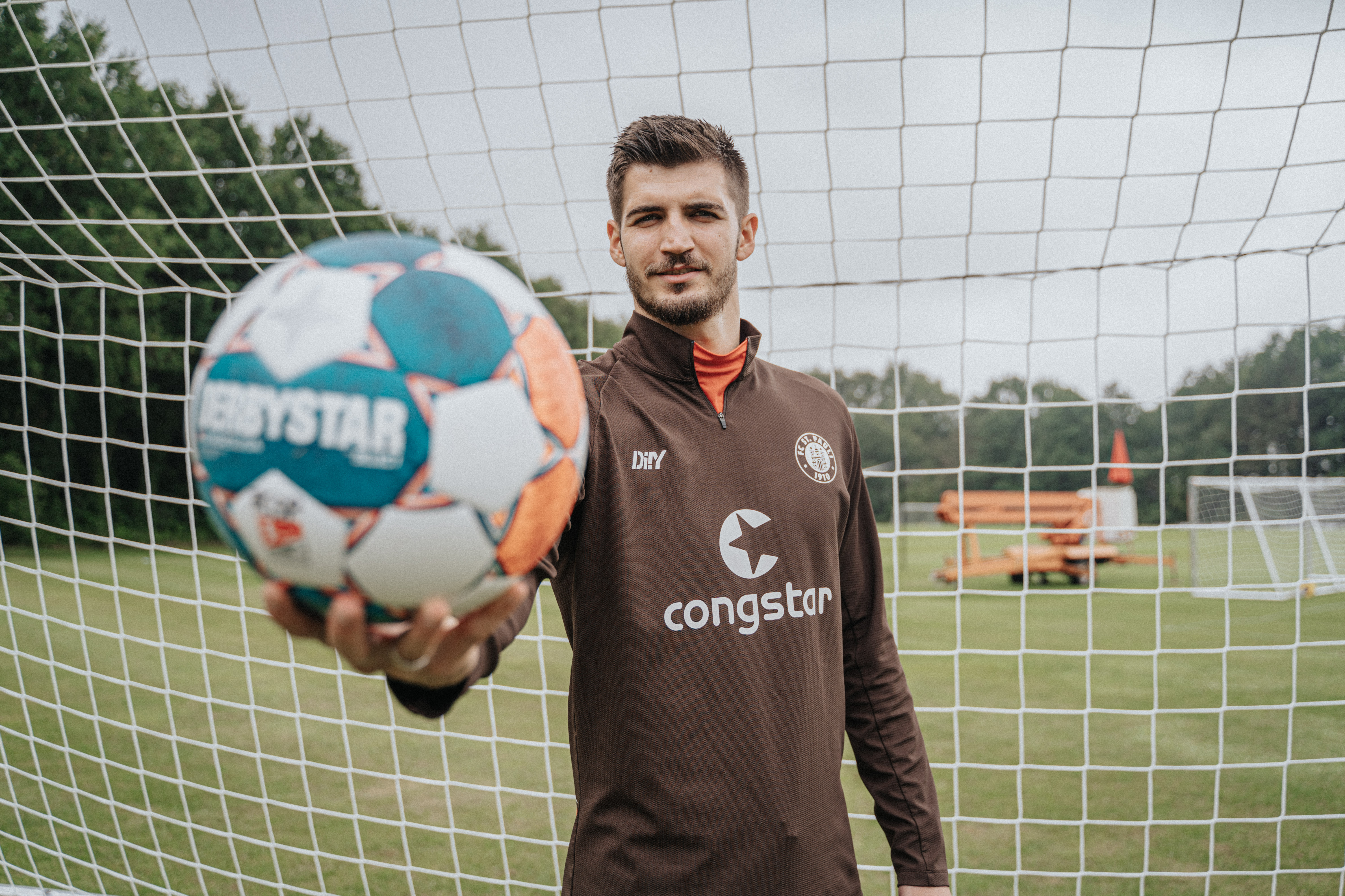 Nikola Vasilj hält einen Fußball in seiner rechten Hand
