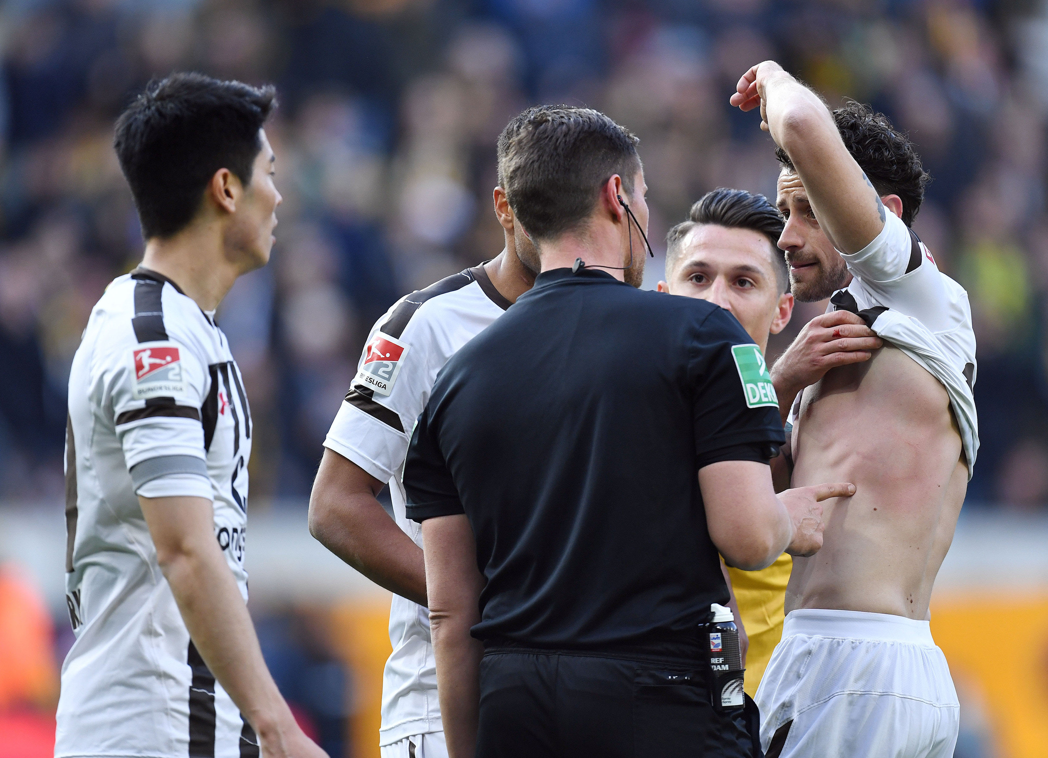 Jan-Philipp Kalla shows referee Robert Kempter the mark left by the ball on his upper body.